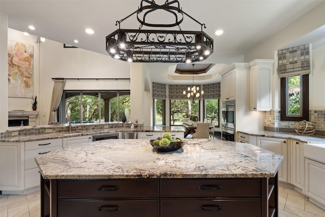 kitchen featuring backsplash, white cabinetry, a center island, and dark brown cabinets