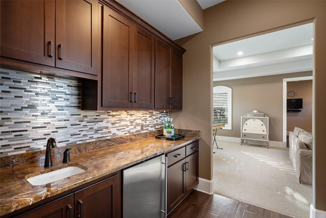 kitchen featuring sink, stainless steel fridge, stone countertops, and tasteful backsplash