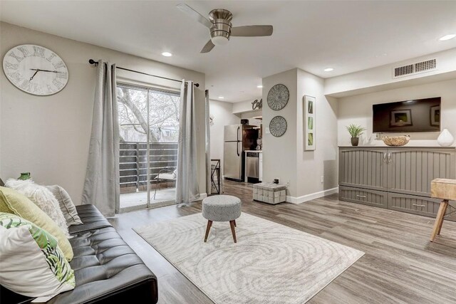 living room with light hardwood / wood-style floors and ceiling fan