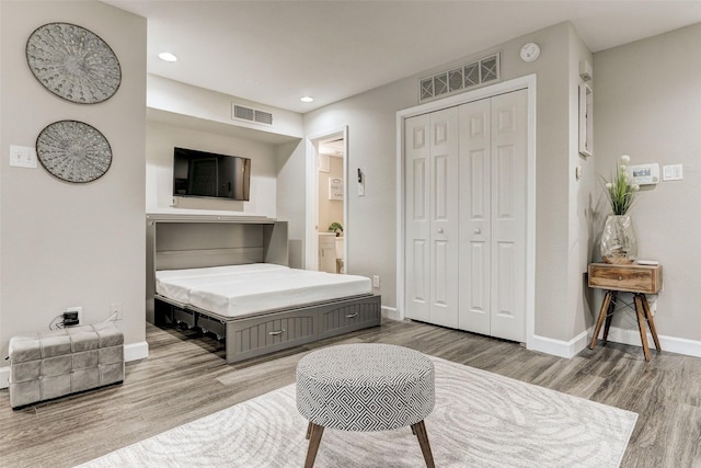 bedroom with visible vents, baseboards, a closet, and wood finished floors