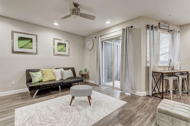 living area featuring ceiling fan, baseboards, and wood finished floors