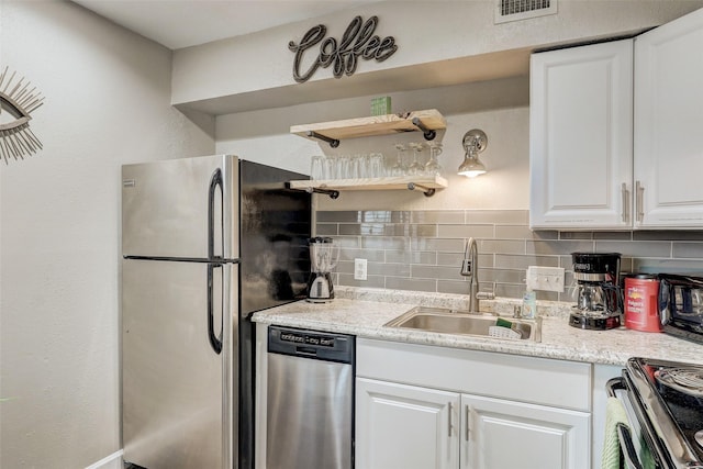 kitchen with light stone countertops, tasteful backsplash, sink, white cabinets, and stainless steel appliances