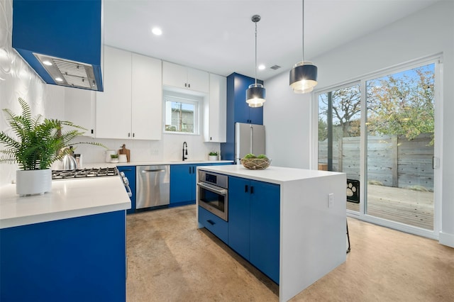 kitchen featuring hanging light fixtures, appliances with stainless steel finishes, white cabinets, a kitchen island, and decorative backsplash