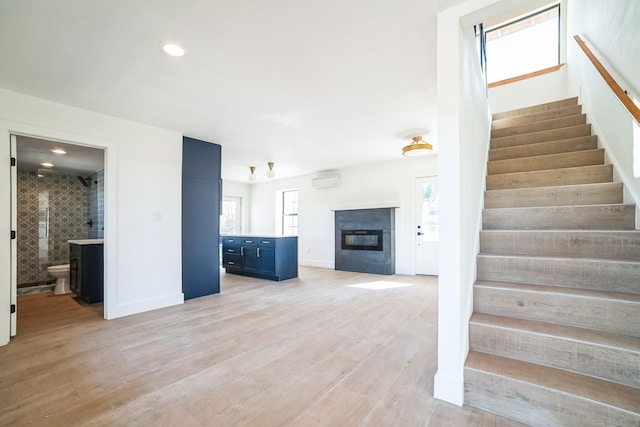 unfurnished living room with light wood-type flooring and a wall mounted AC