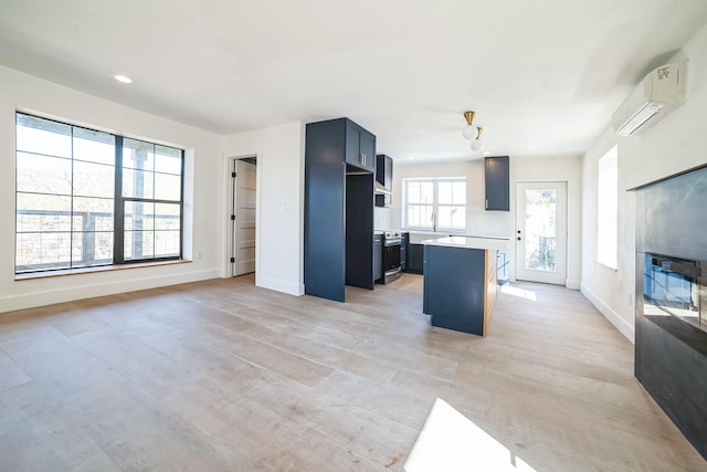 kitchen with a kitchen island, plenty of natural light, a wall mounted air conditioner, and a breakfast bar