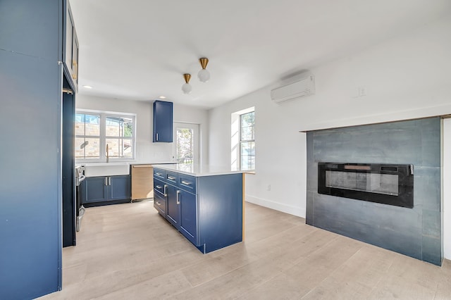 kitchen with light wood-type flooring, a wall unit AC, a kitchen island, and blue cabinets