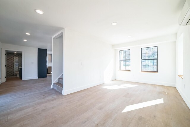 empty room featuring light hardwood / wood-style flooring and a wall unit AC