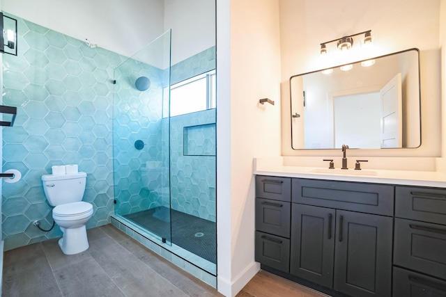 bathroom with vanity, toilet, tile walls, and a tile shower