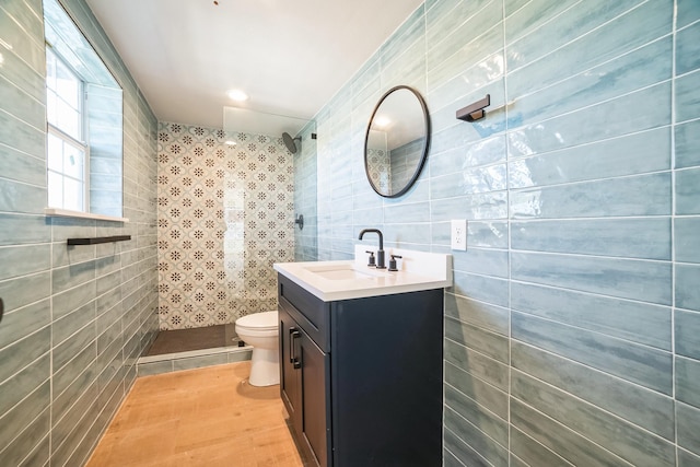 bathroom with toilet, a shower, tile walls, and vanity