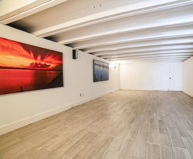 unfurnished room with light hardwood / wood-style floors and beamed ceiling