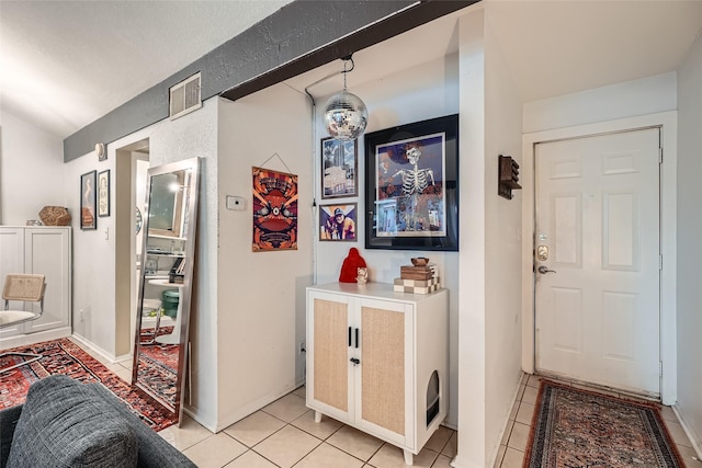 hall with vaulted ceiling and light tile patterned floors