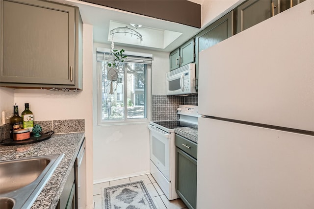 kitchen featuring sink, light tile patterned floors, green cabinets, white appliances, and backsplash