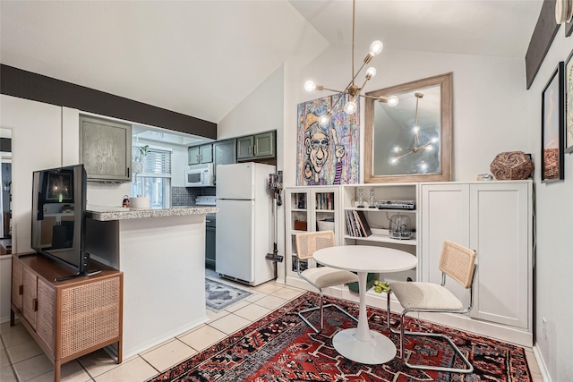 kitchen with lofted ceiling, white appliances, light tile patterned flooring, decorative light fixtures, and kitchen peninsula