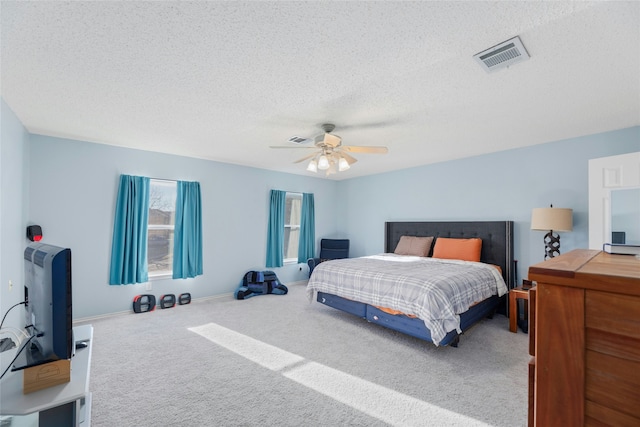 carpeted bedroom with ceiling fan and a textured ceiling