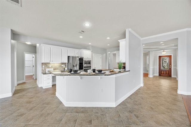 kitchen with appliances with stainless steel finishes, white cabinetry, stone countertops, backsplash, and kitchen peninsula