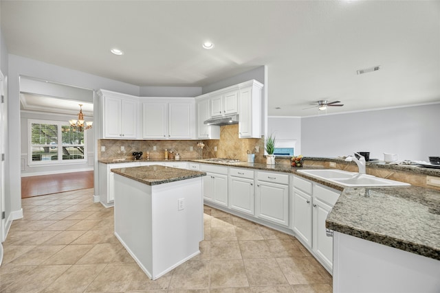 kitchen featuring a center island, dark stone counters, white cabinetry, and sink