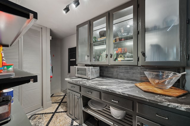 kitchen featuring tasteful backsplash, light tile patterned floors, and stone counters