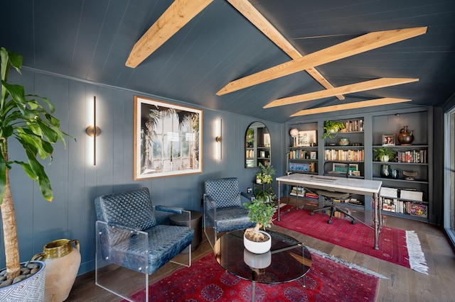 interior space with built in shelves, lofted ceiling with beams, hardwood / wood-style floors, and wooden walls