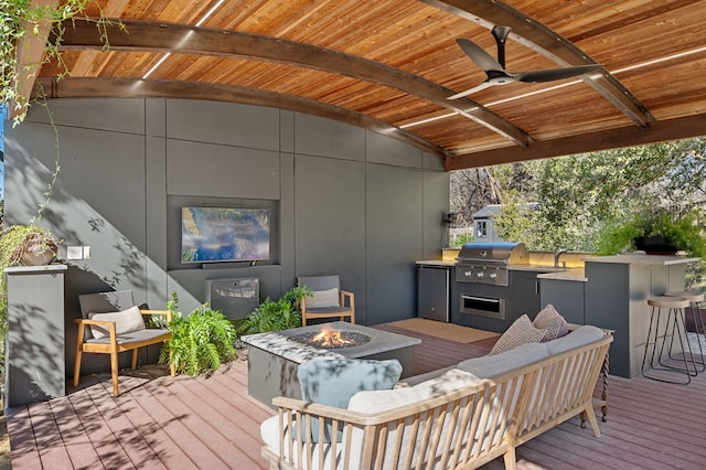 wooden deck featuring an outdoor living space with a fire pit, an outdoor kitchen, ceiling fan, an outdoor bar, and grilling area