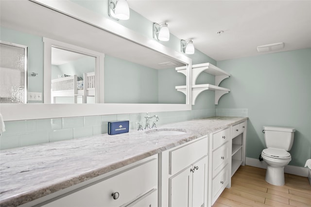 bathroom featuring toilet, vanity, and tasteful backsplash