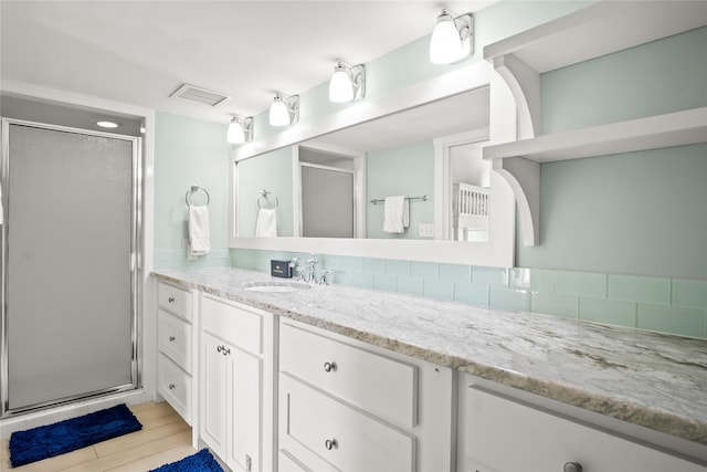 bathroom featuring a shower with door and vanity