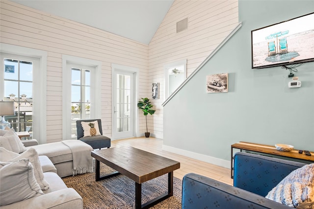 living room featuring high vaulted ceiling, wood walls, and hardwood / wood-style floors