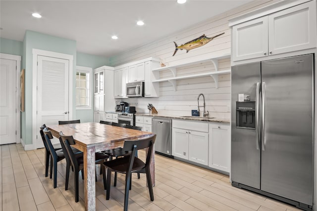 kitchen featuring sink, stainless steel appliances, white cabinetry, and light stone counters