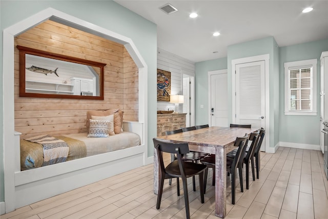 dining area with wood walls and light hardwood / wood-style floors