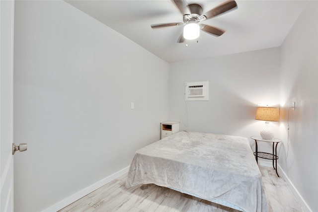 bedroom featuring light hardwood / wood-style floors, a wall unit AC, and ceiling fan