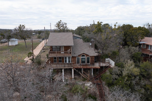 back of house featuring a balcony and a wooden deck