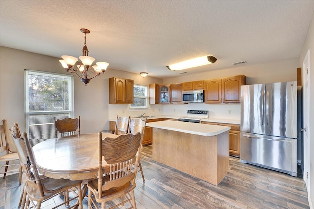 kitchen with pendant lighting, a center island, stainless steel appliances, sink, and dark hardwood / wood-style floors