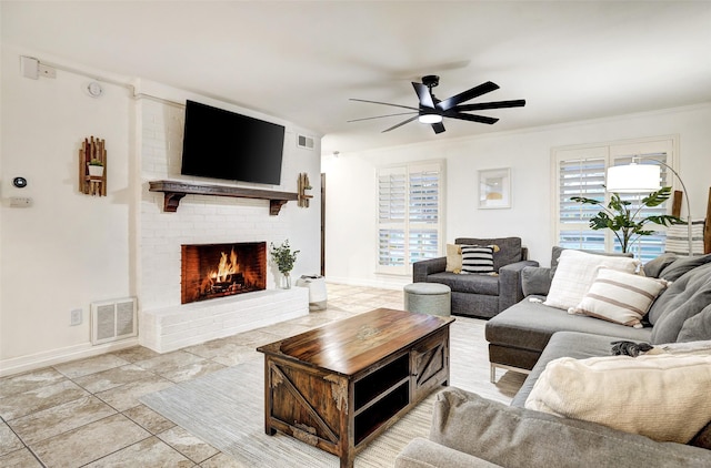 living room with a brick fireplace, crown molding, and ceiling fan