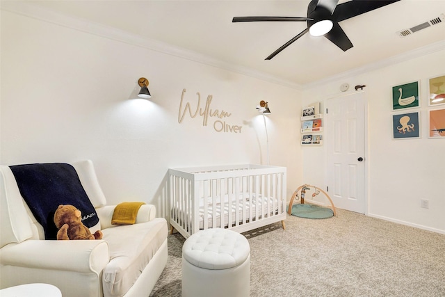 carpeted bedroom with ceiling fan, ornamental molding, and a crib