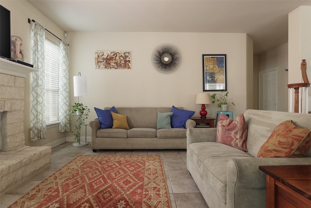 tiled living room featuring a stone fireplace