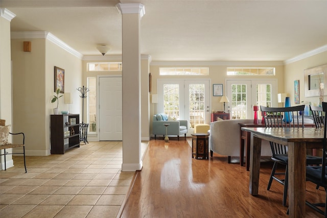 foyer with crown molding, french doors, ornate columns, and light wood-type flooring