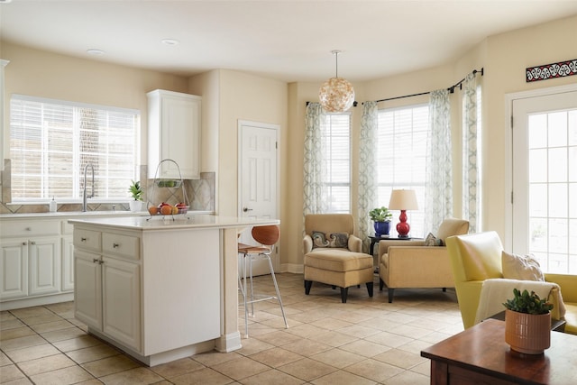 kitchen featuring white cabinets, pendant lighting, a kitchen island, and a wealth of natural light