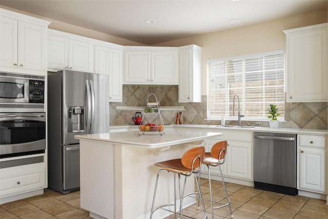 kitchen featuring white cabinetry, a kitchen island, sink, light tile patterned floors, and appliances with stainless steel finishes