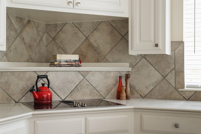 interior details with white cabinetry, backsplash, and black electric cooktop