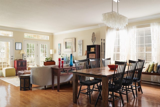 dining space featuring hardwood / wood-style flooring, a chandelier, crown molding, and french doors