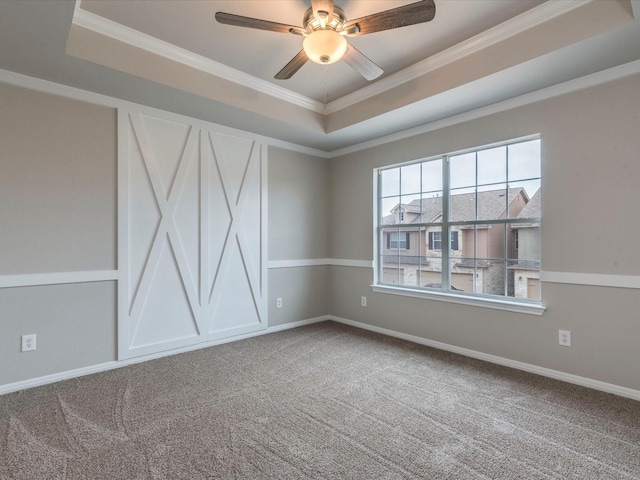 empty room with ceiling fan, crown molding, carpet floors, and a tray ceiling