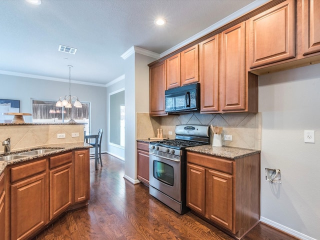 kitchen featuring crown molding, hanging light fixtures, dark stone countertops, dark wood-type flooring, and stainless steel range with gas stovetop