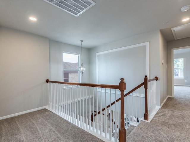 corridor featuring a notable chandelier and carpet flooring