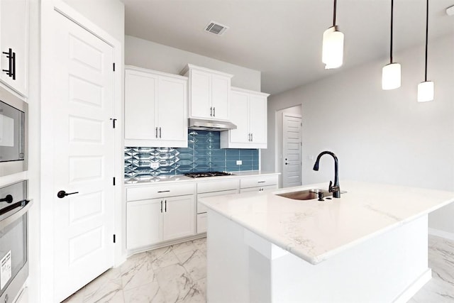 kitchen with an island with sink, hanging light fixtures, and white cabinets