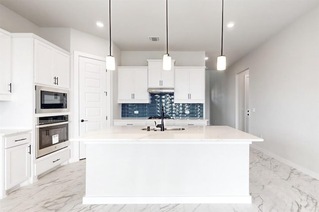 kitchen with black microwave, white cabinets, hanging light fixtures, stainless steel oven, and a center island with sink