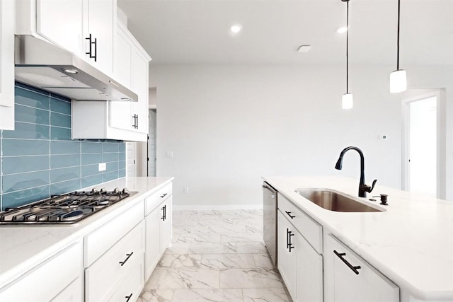 kitchen featuring appliances with stainless steel finishes, decorative light fixtures, white cabinetry, sink, and a center island with sink