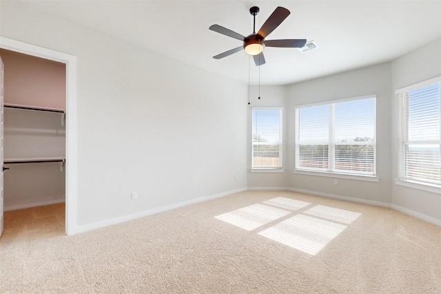 unfurnished bedroom with ceiling fan, a walk in closet, light colored carpet, and a closet