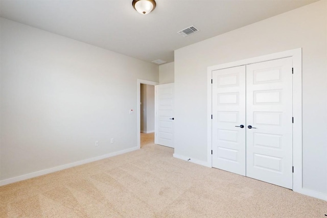 unfurnished bedroom featuring light carpet and a closet