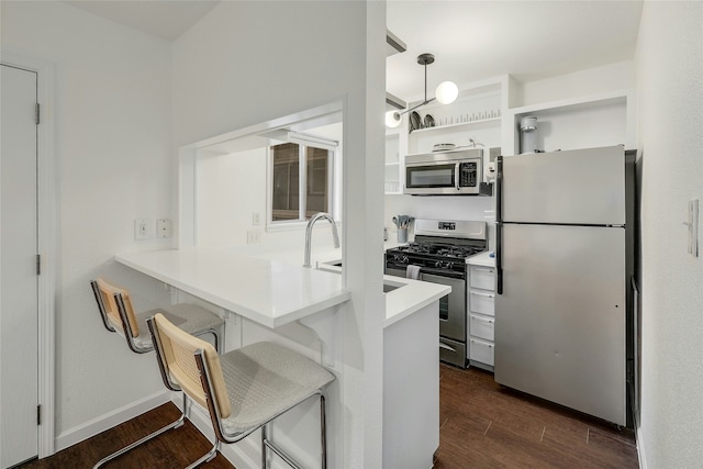 kitchen featuring white cabinetry, stainless steel appliances, hanging light fixtures, kitchen peninsula, and a breakfast bar area