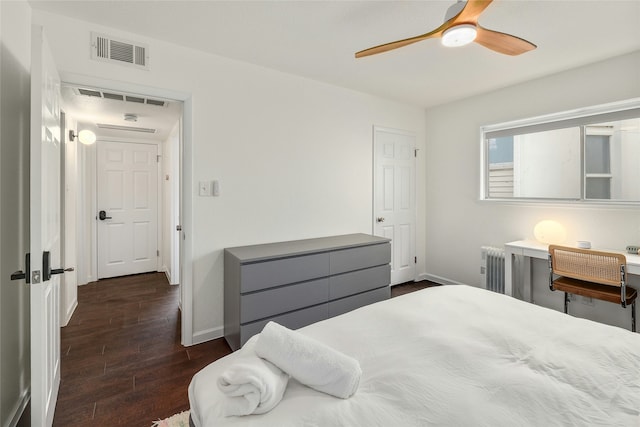 bedroom with dark hardwood / wood-style floors, ceiling fan, and radiator