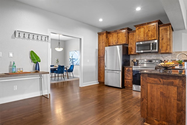 kitchen featuring decorative light fixtures, dark wood-type flooring, tasteful backsplash, and appliances with stainless steel finishes